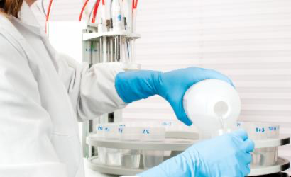 Laboratorietekniker som heller væske med blå Granberg 951 nitrilhansker med lang mansjett