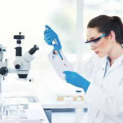 Laboratorietekniker med blå Granberg 951 nitrilhansker som pipetterer ved mikroskop