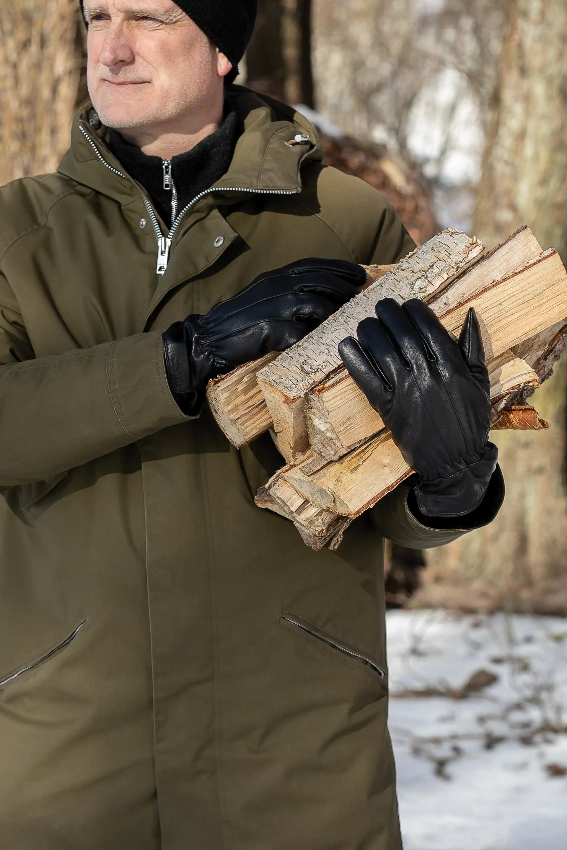 Mann bærer ved med Granberg 119.1101 svarte skinnhansker – vinterhansker med ullfôr for utendørs bruk