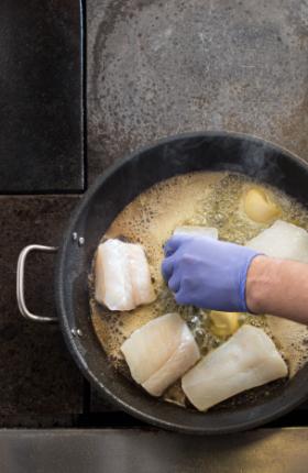 Granberg 624 indigo Soft Nitrile engangshansker i bruk ved steking av fisk i stekepanne – matgodkjent hanske for kjøkken
