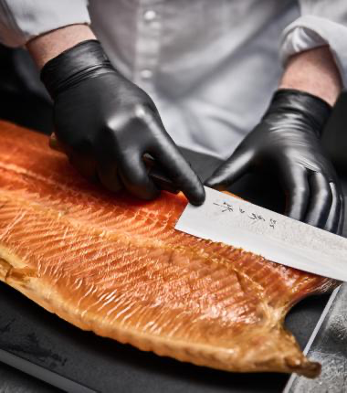 Kokk skjærer laks med Granberg 633 svarte nitrilhansker – Soft Nitrile, pudderfri og matgodkjent