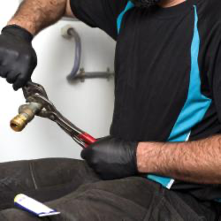 Rørlegger med Granberg 880 svarte nitril engangshansker som strammer messingkobling med tang – pudderfri hanske med godt grep