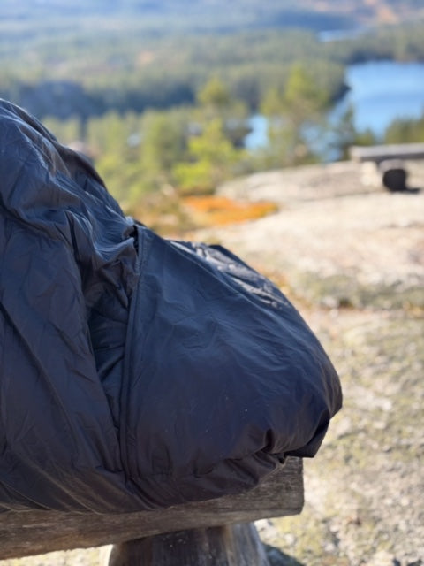 nærbilde av utekos mikrofiber™-stoff som dekker beina til en person på benk med fjellutsikt